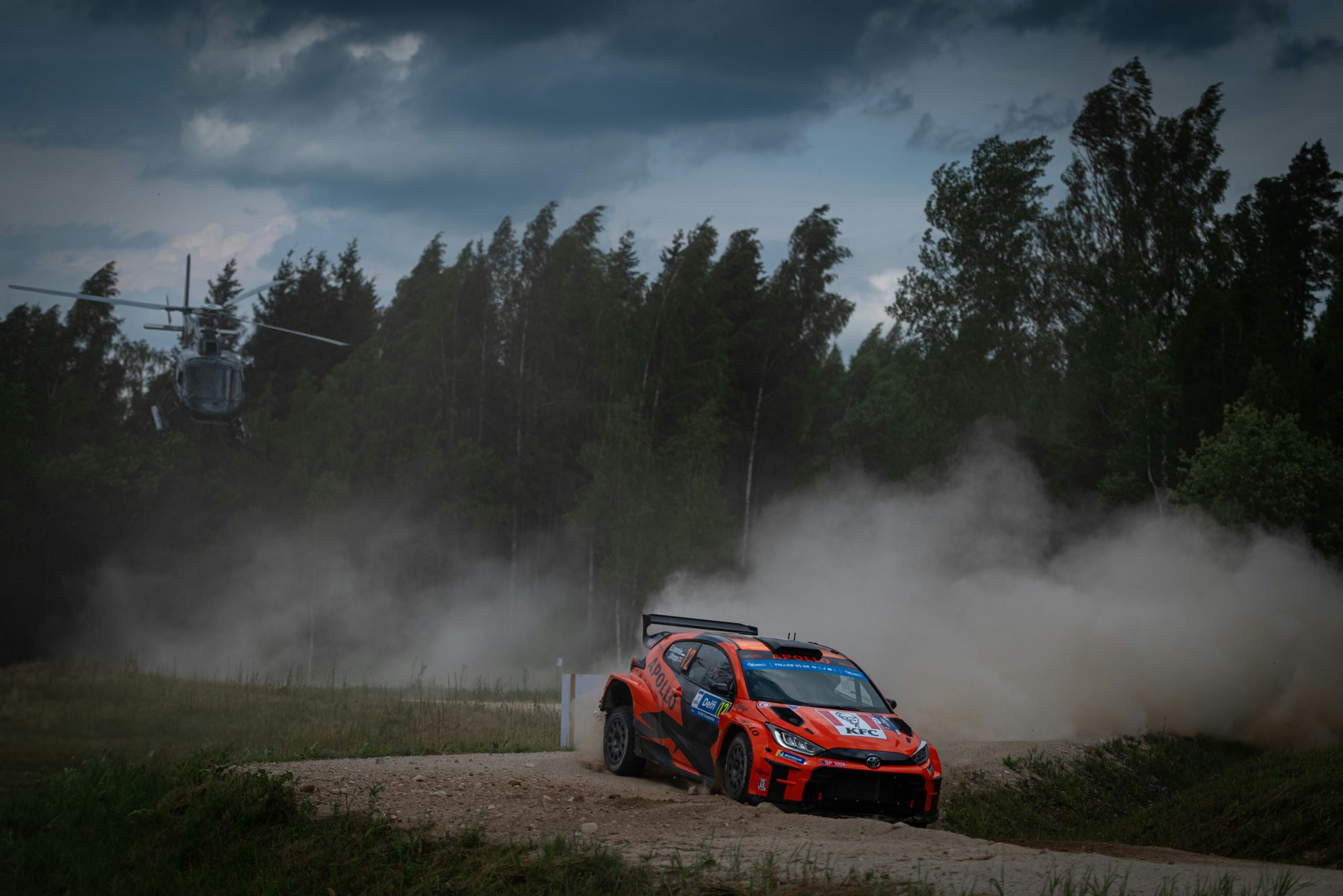 Rally car driving along a gravel road through forest